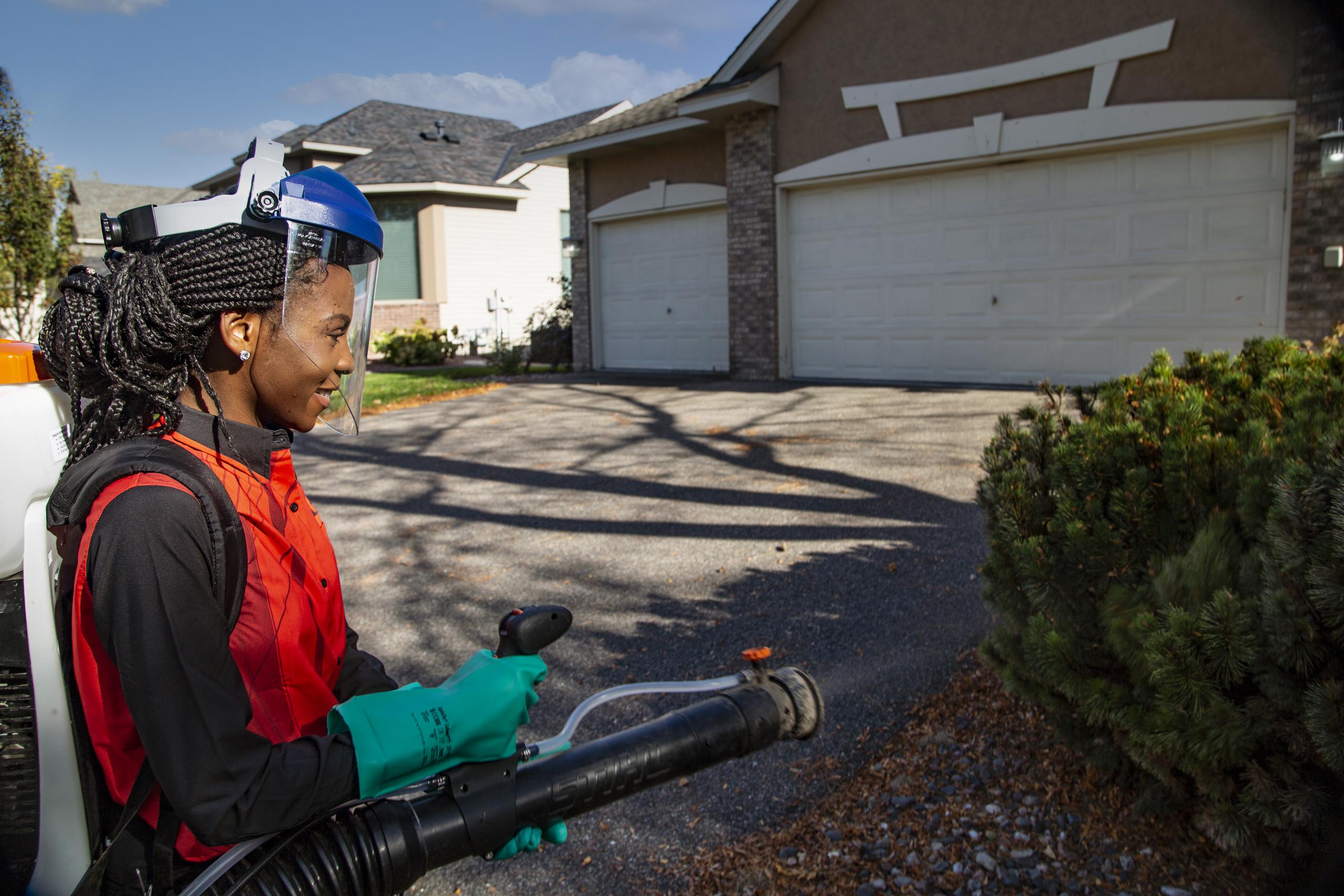 pest control technician treating home landscape