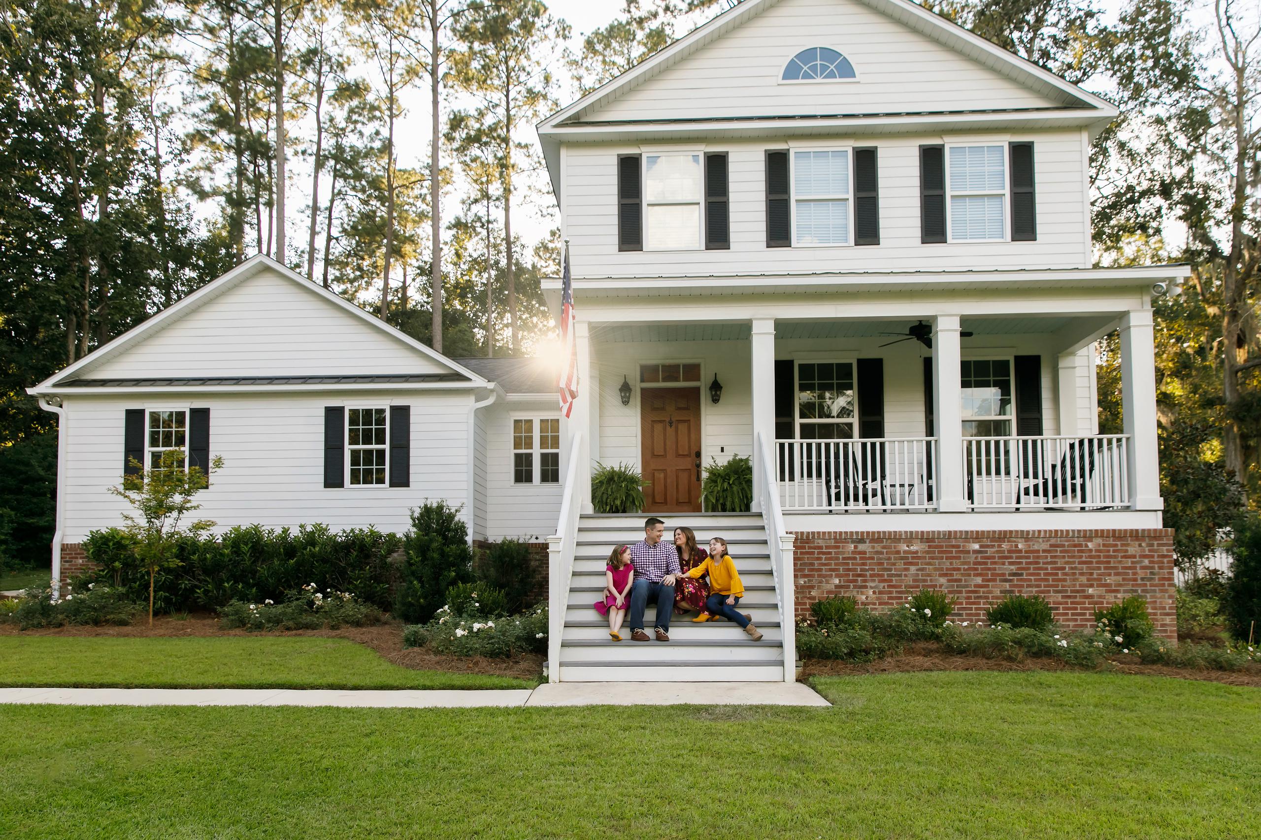 family sitting on front steps of their home