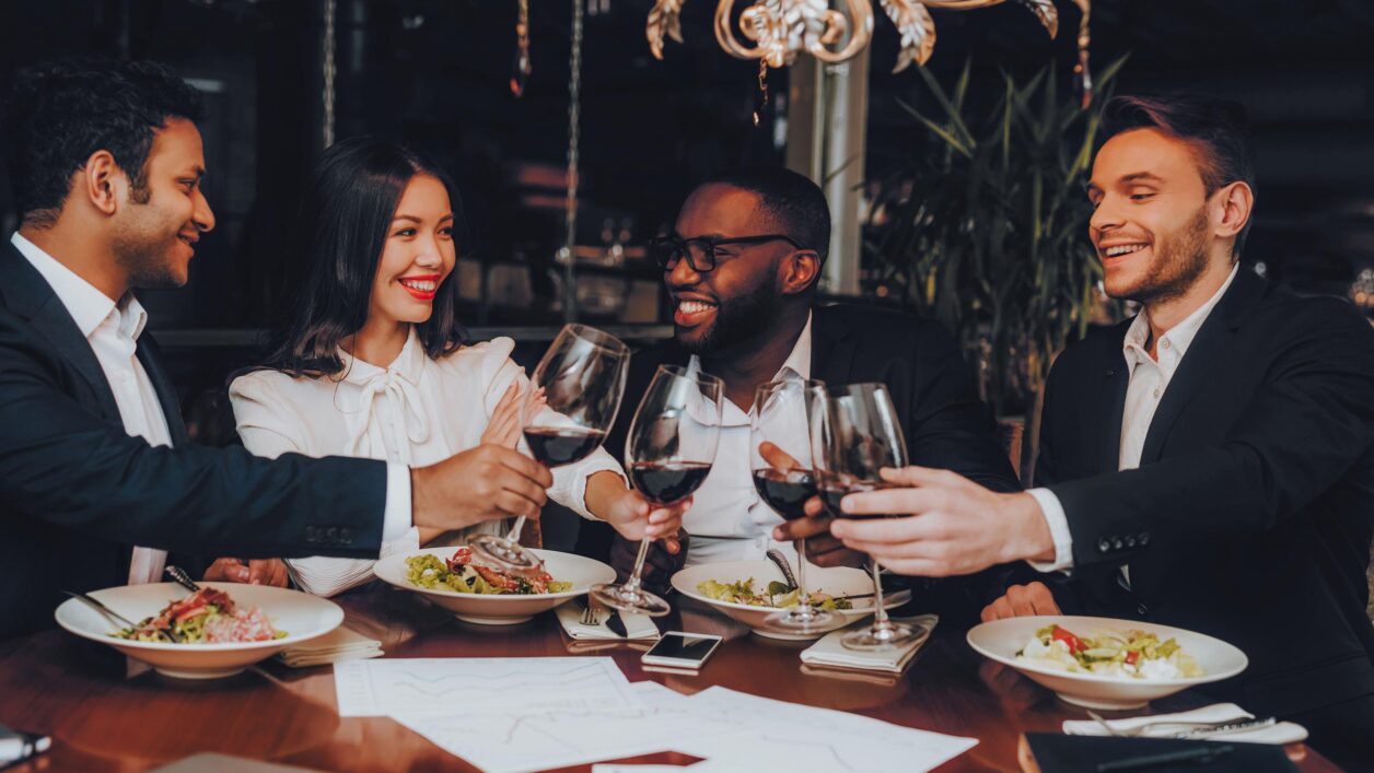 young adults toasting with wine while dining