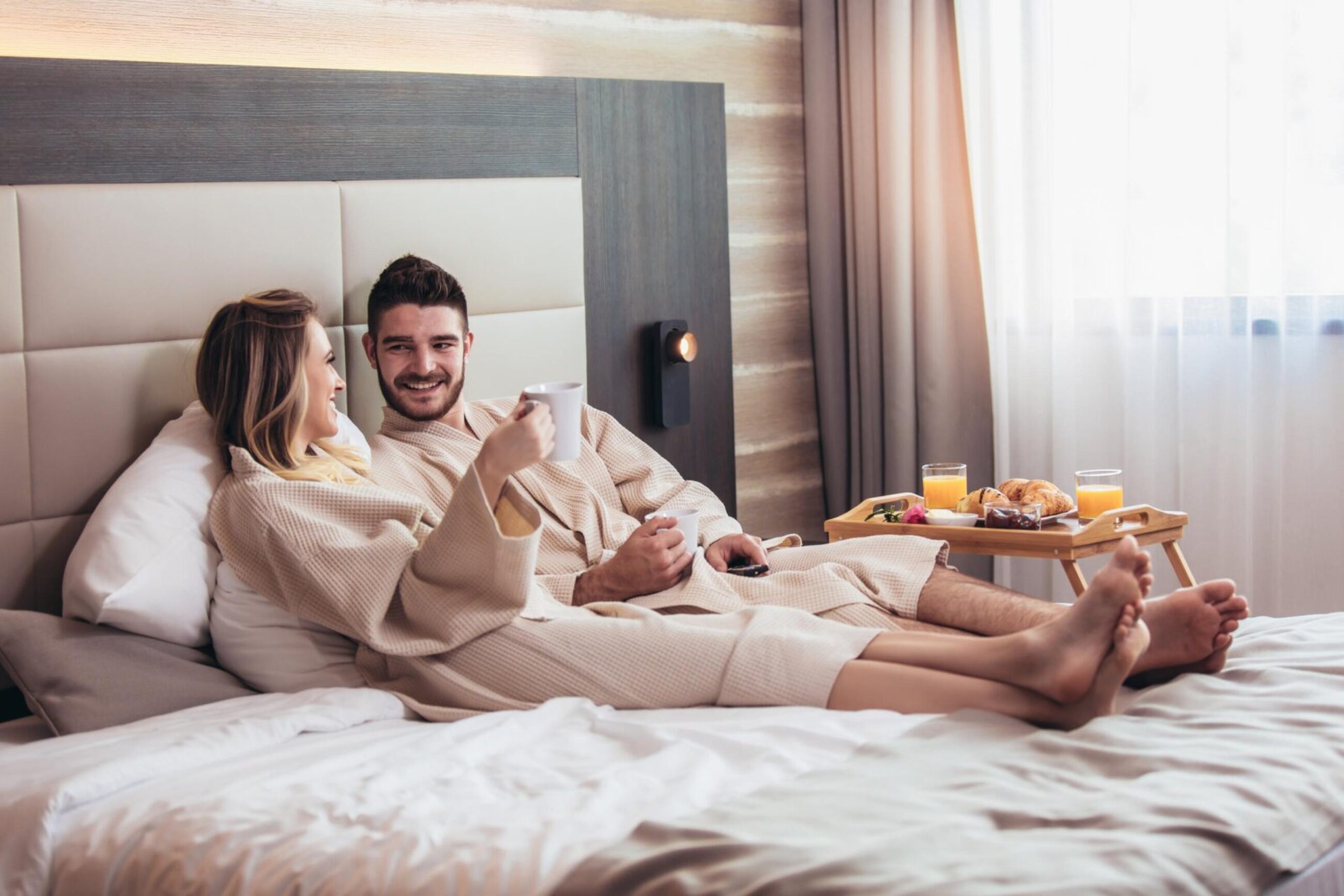 couple in bathrobes enjoying coffee and breakfast in bed at a luxury hotel couple enjoying breakfast in bed