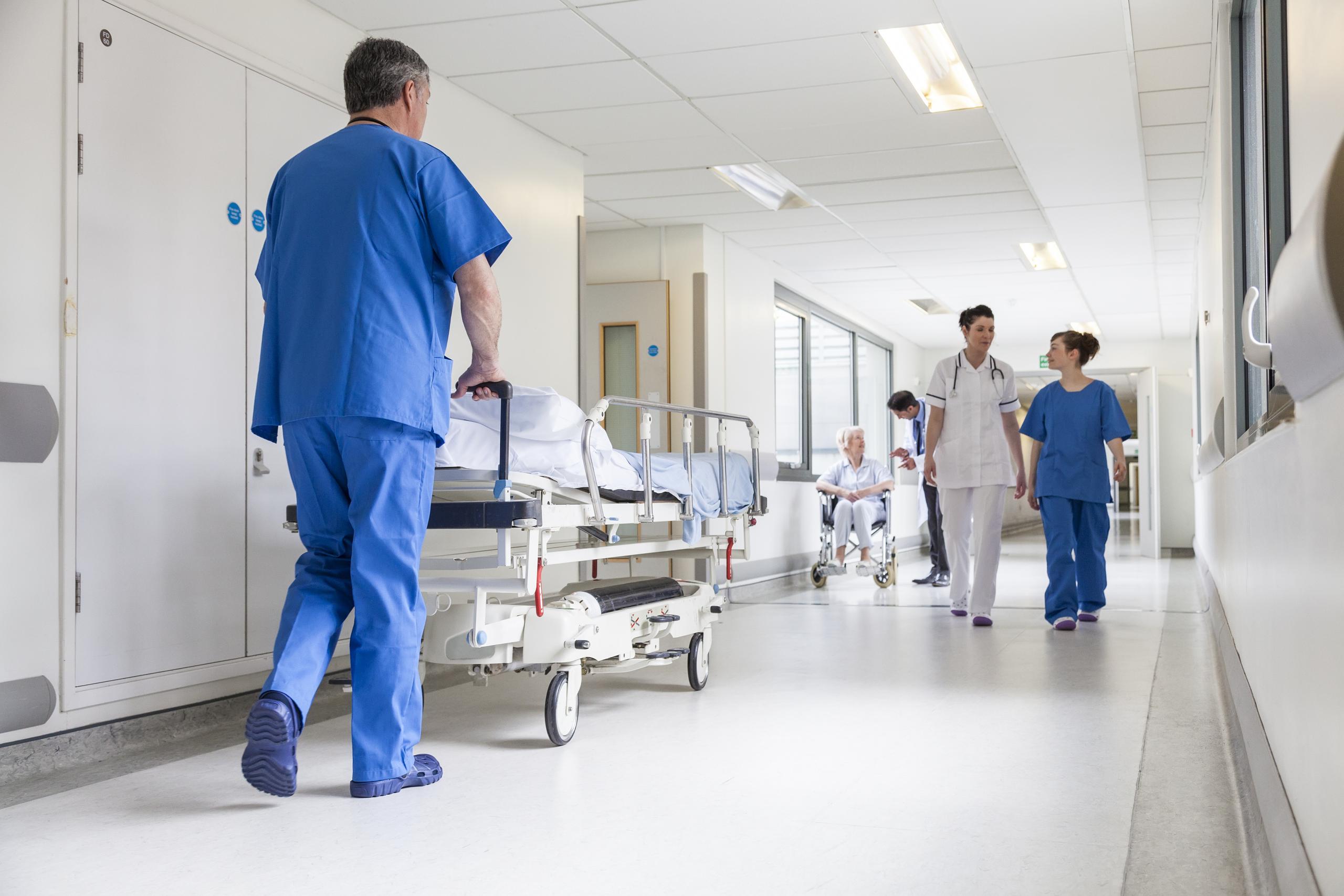 man pushing hospital bed down hallway