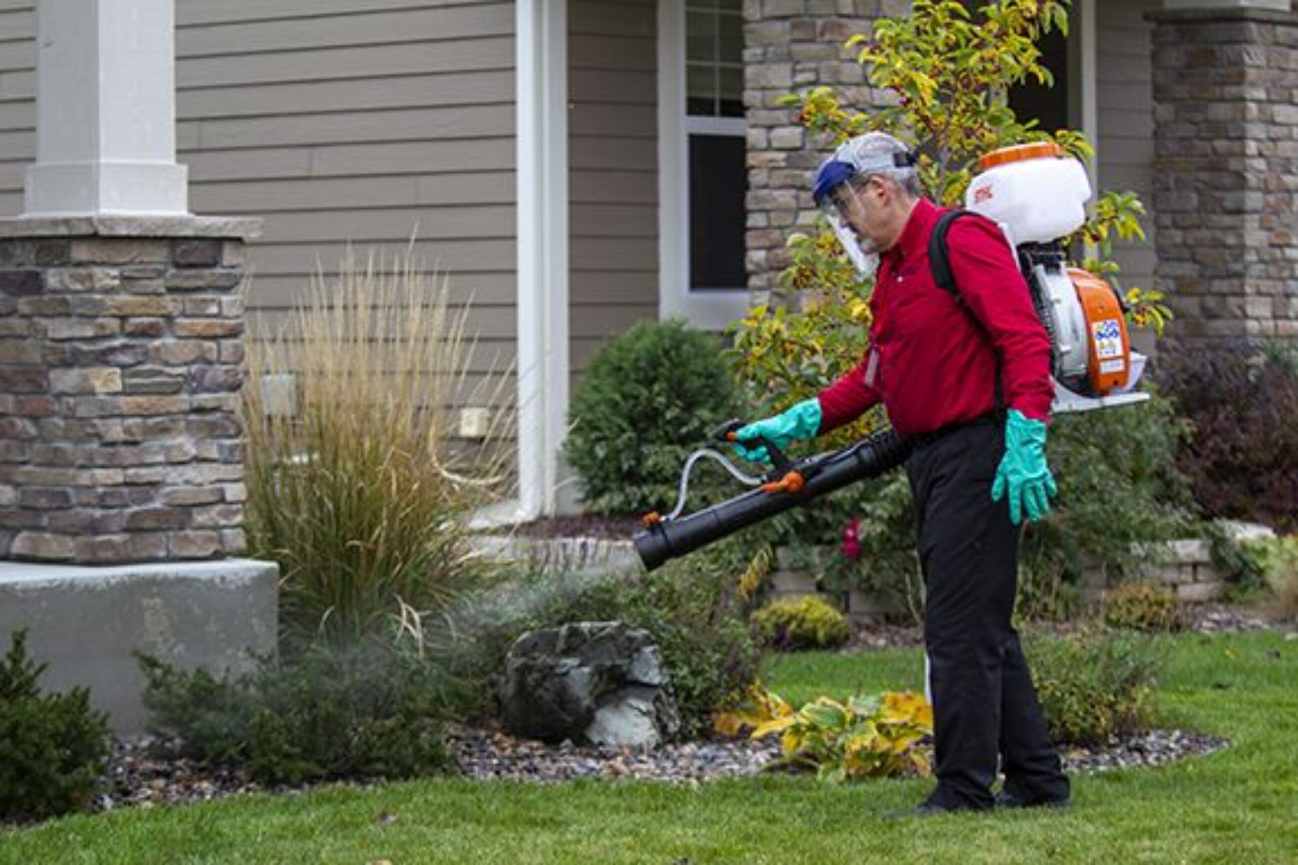 adam's pest control tech spraying for pests outoors