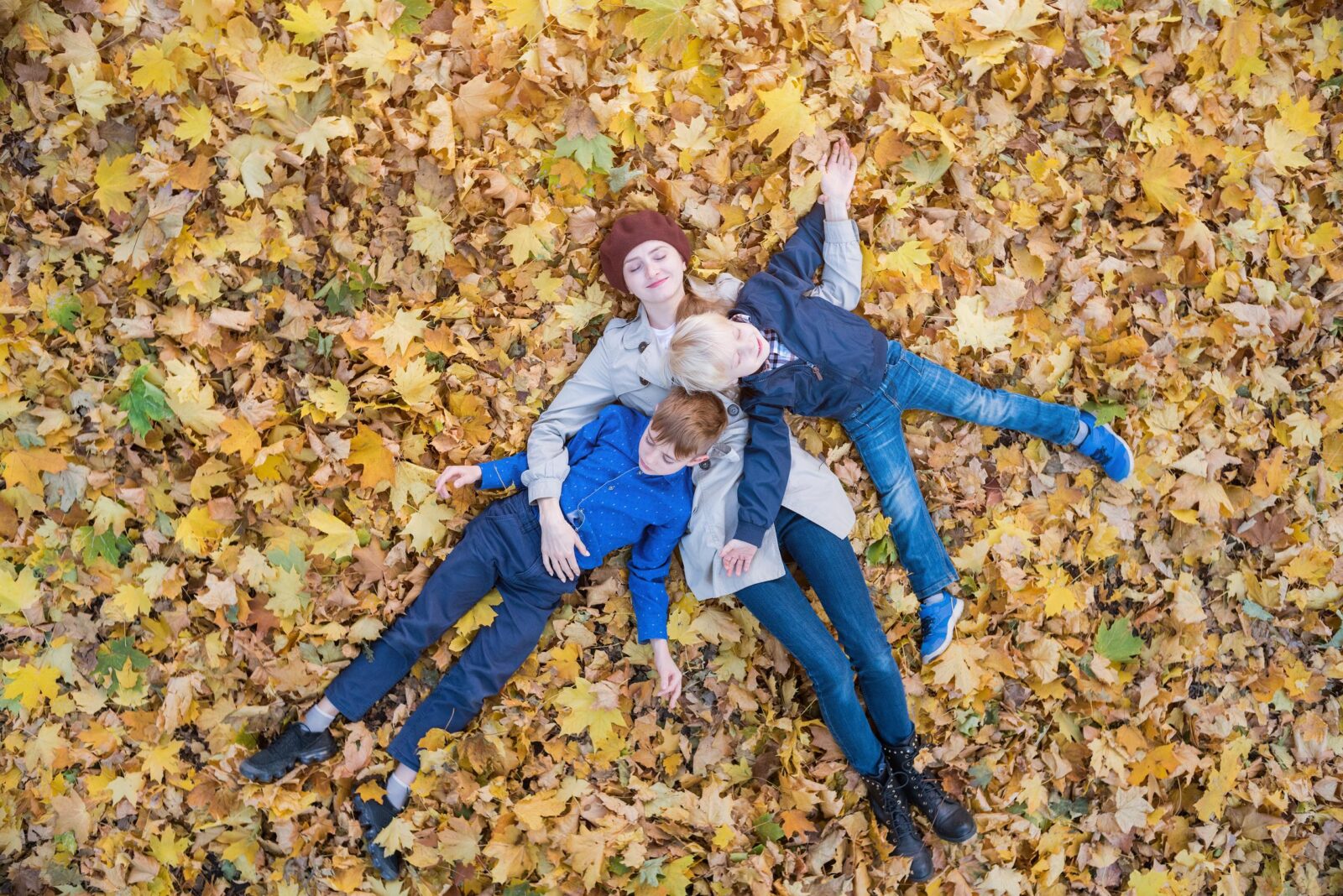mom and sons laying in the leaves